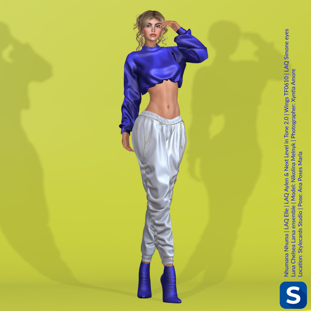 A full-length photo of Nikolina Melnyk posing in front of a bright yellow backdrop. She is wearing a long-sleeved blue crop top, white pants, and blue high heel boots.