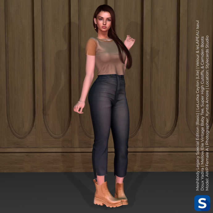 A photo of Female A from the Avatar Starter Pack wearing Female Look Casual. She is standing in front of a wall with wood paneling while wearing a two-tone beige t-shirt, high-water blue jeans, and tan leather boots. She has long brown hair draped around one of her shoulders.