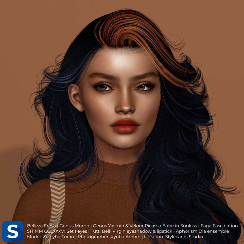 Model Zuleyha Turan is standing in front of an orange backdrop. She has long wavy black hair with an orange streak and is wearing a dark orange sweater and a pinafore dress, while her face has red lipstick and dark eyeshadow.