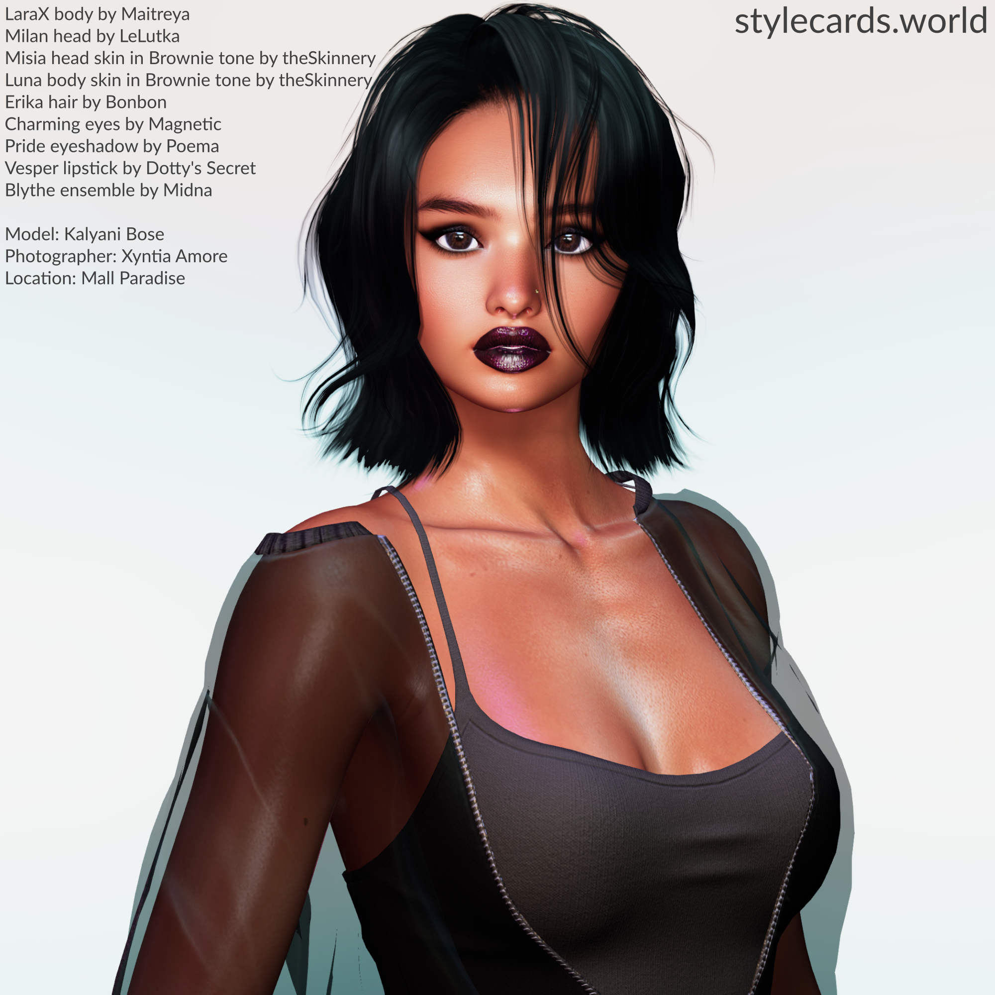 Kalyani Bose poses in front of a white background in a photo booth in the skating rink are a of Mall Paradise in Second Life. She is wearing dark red lipstick, smoky eyeshadow, a black tank top, and a sheer black jacket.