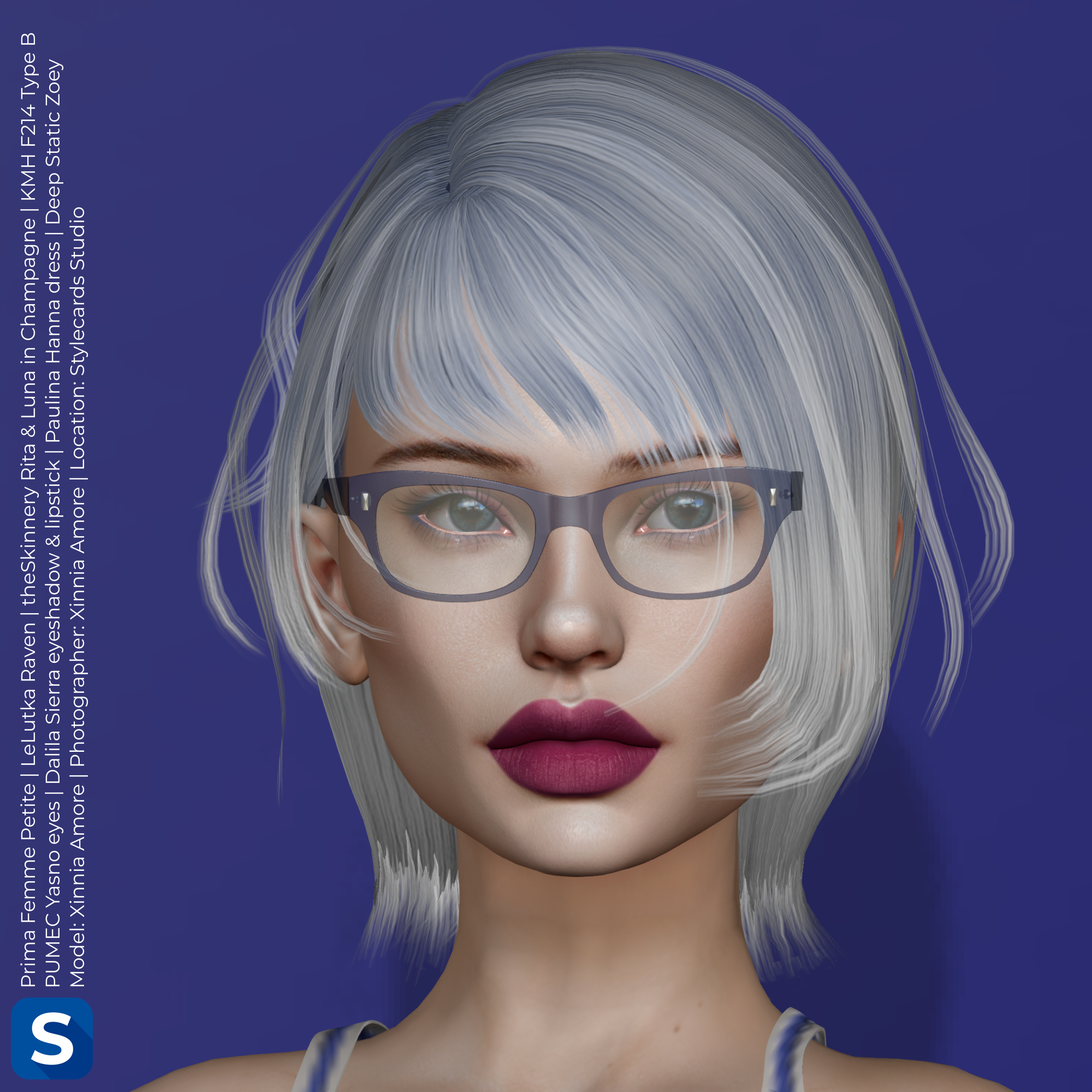 A headshot of Xinnia Amore standing in front of a blue backdrop in the studio. Her short hair is mostly with with some blue streaks, while her face is adorned with a pair of blue framed eyeglasses. Her eyeshadow is a subtle mix of blue while her lipstick is a pale burgundy.