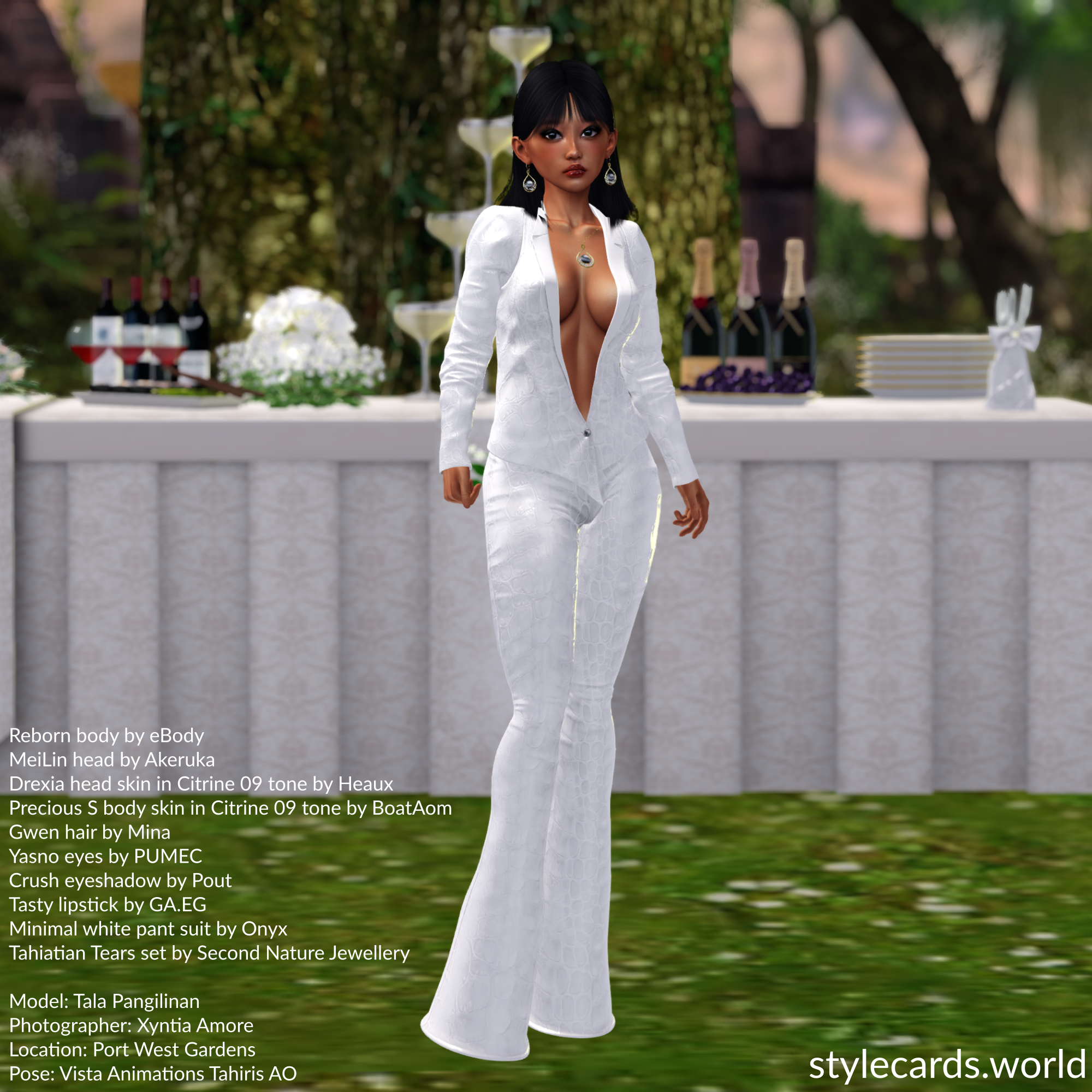 Tala Pangilinan is wearing a white leather suit that's accessorized with a gold and pearl earring and necklace set. She is posing at an outdoor wedding venue in front of a banquet table adorned with flower arrangements and bottles of champagne.