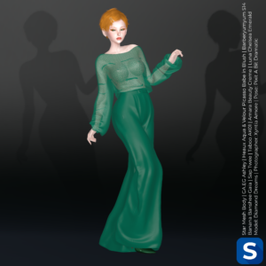 Diamond Dreams poses in a green ensemble featuring a lace blouse and satin pants. Her hair is short and bright red, and she is standing in front of a black backdrop.