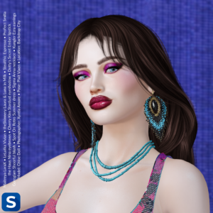 A headshot of Chloe Doll standing in front of a blue backdrop. She has long brown hair, a pink sequined dress, a turquoise-beaded necklace, beaded earrings, magenta eyeshadow, and plum lipstick.