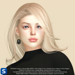 A headshot of a woman with long blonde hair standing in front of a pale yellow backdrop. She has pale blue eyeshadow, pale pink lipstick, and skull-shaped earrings in black to match the color of her sweater.